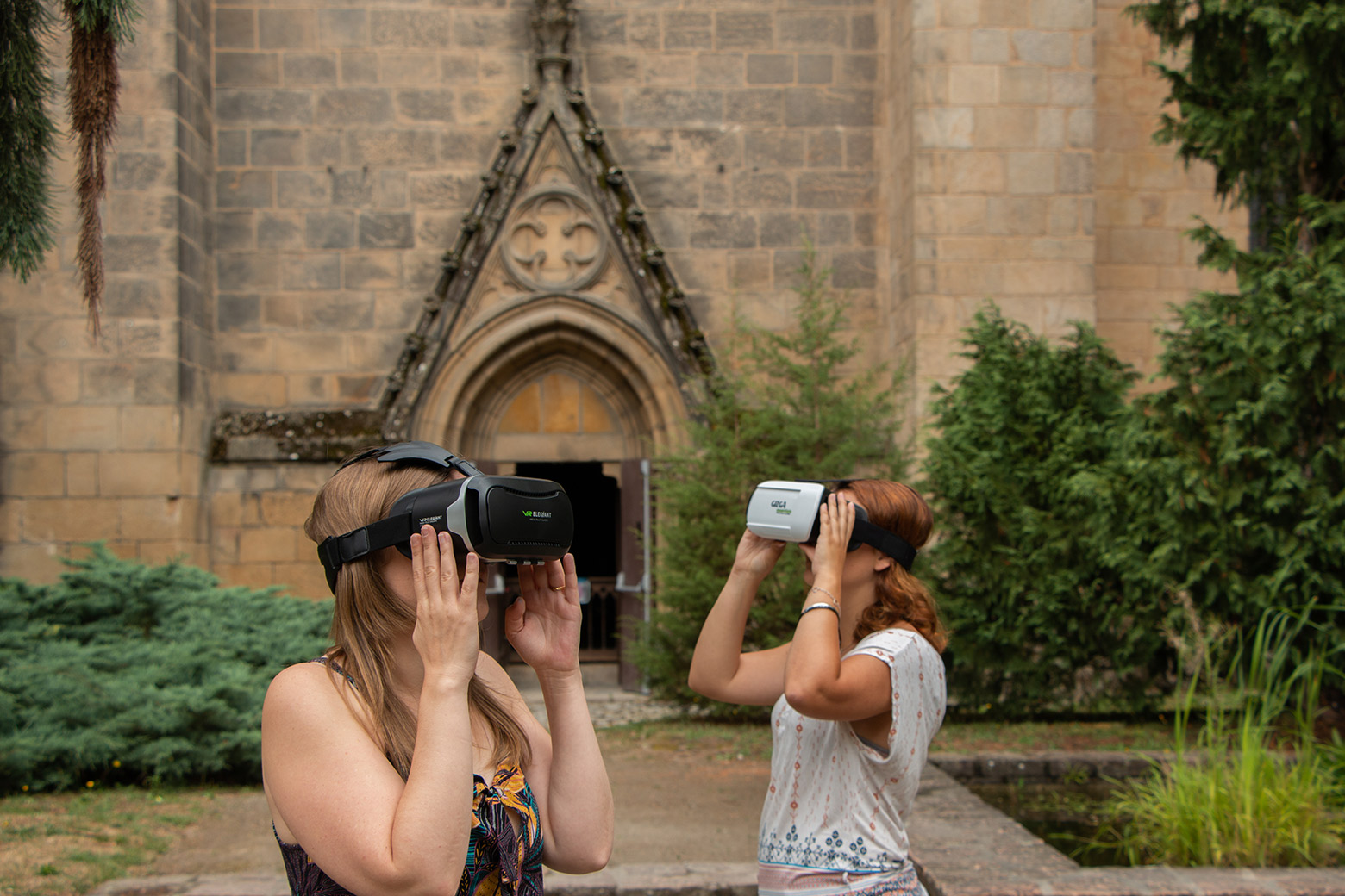 Deux jeunes femmes qui portent des casques VR devant une cathédrale