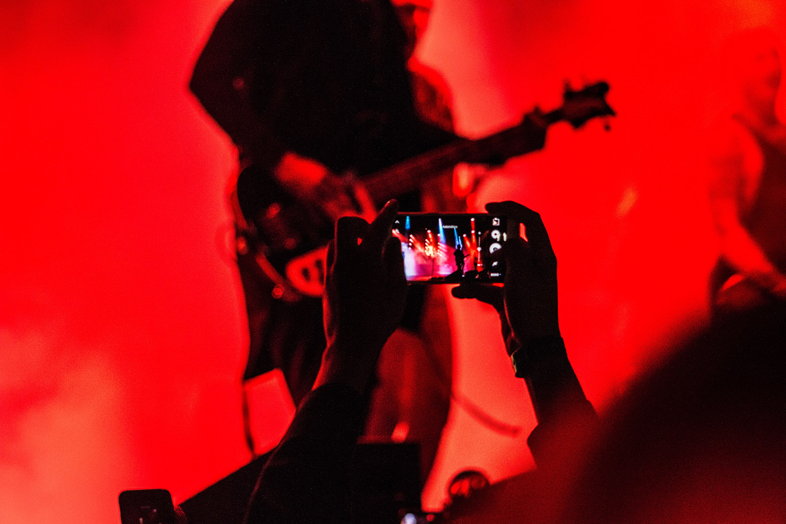 une personne qui filme un guitariste avec son smartphone