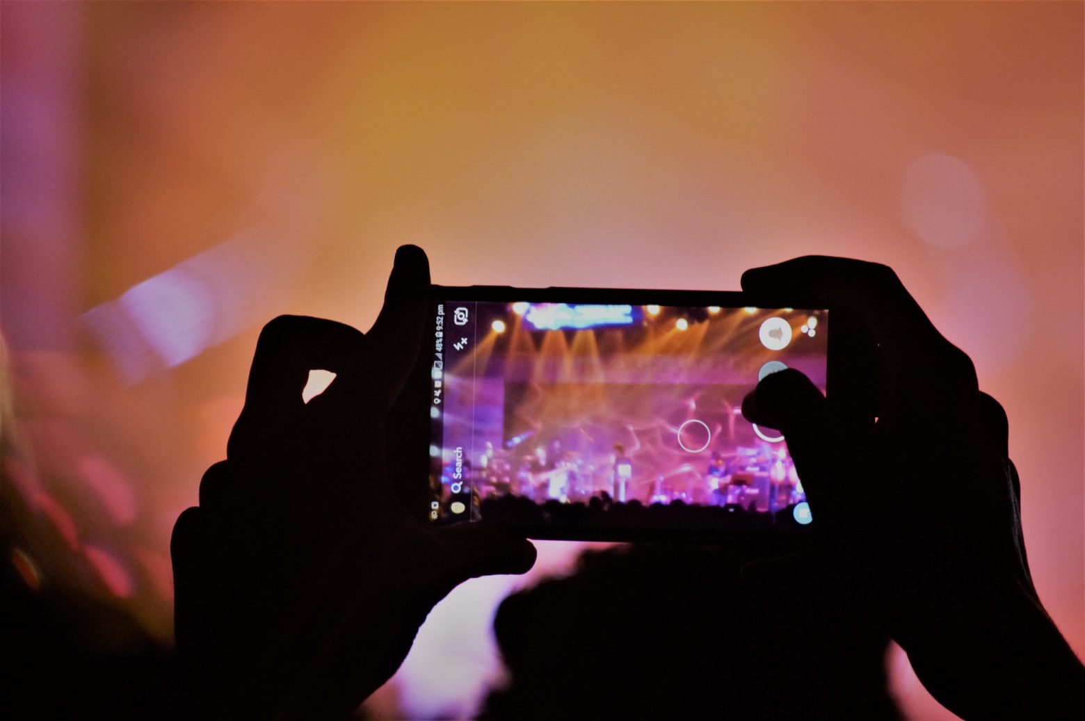 Une personne qui est en train de filmer un concert avec un smartphone